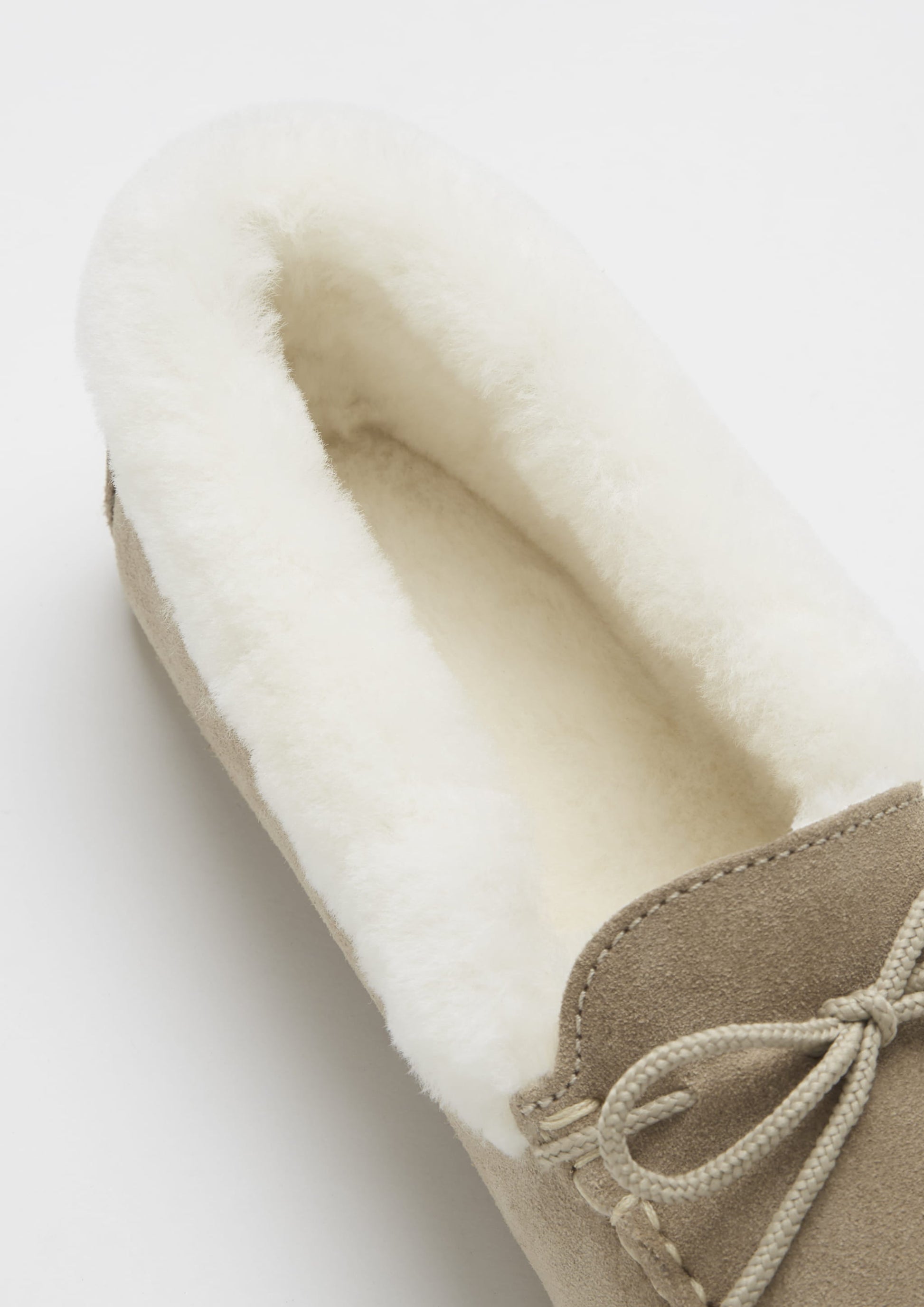 Close-up of a beige slipper with white interior on a light background