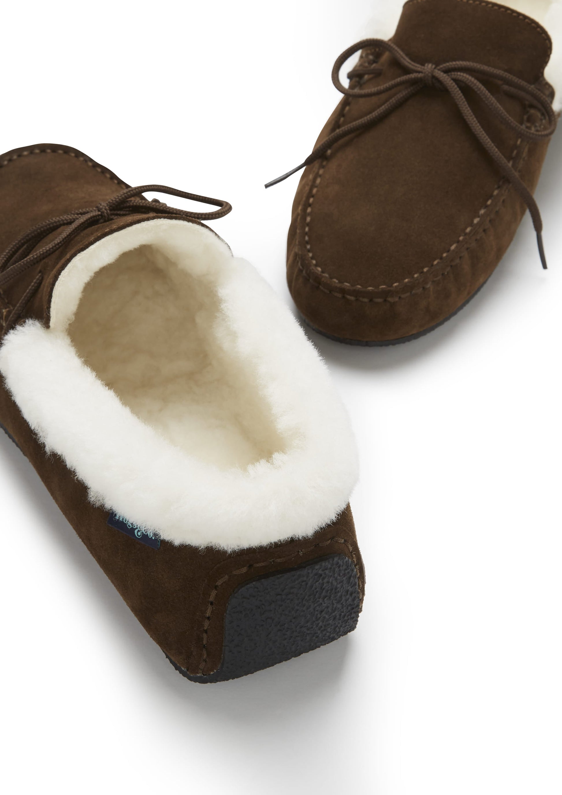 Brown suede moccasin slippers with white fur lining on a white background