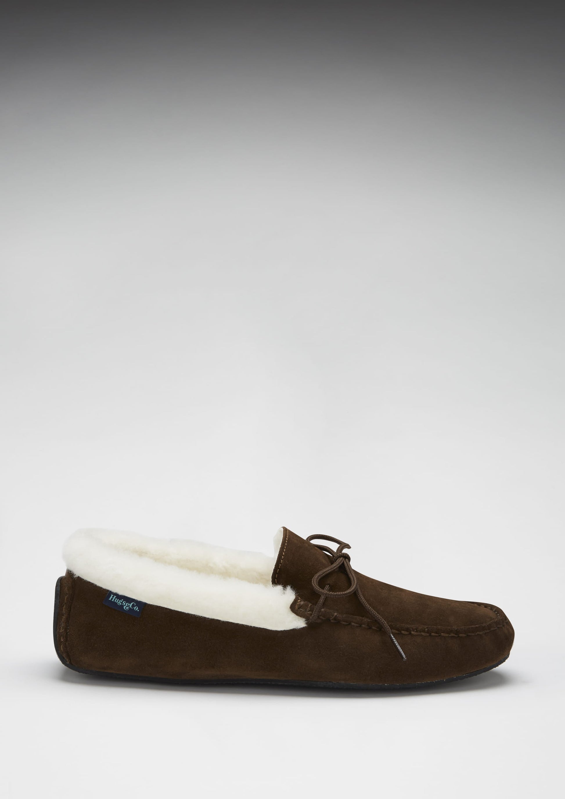 Brown suede slipper with white fur lining on a gray background
