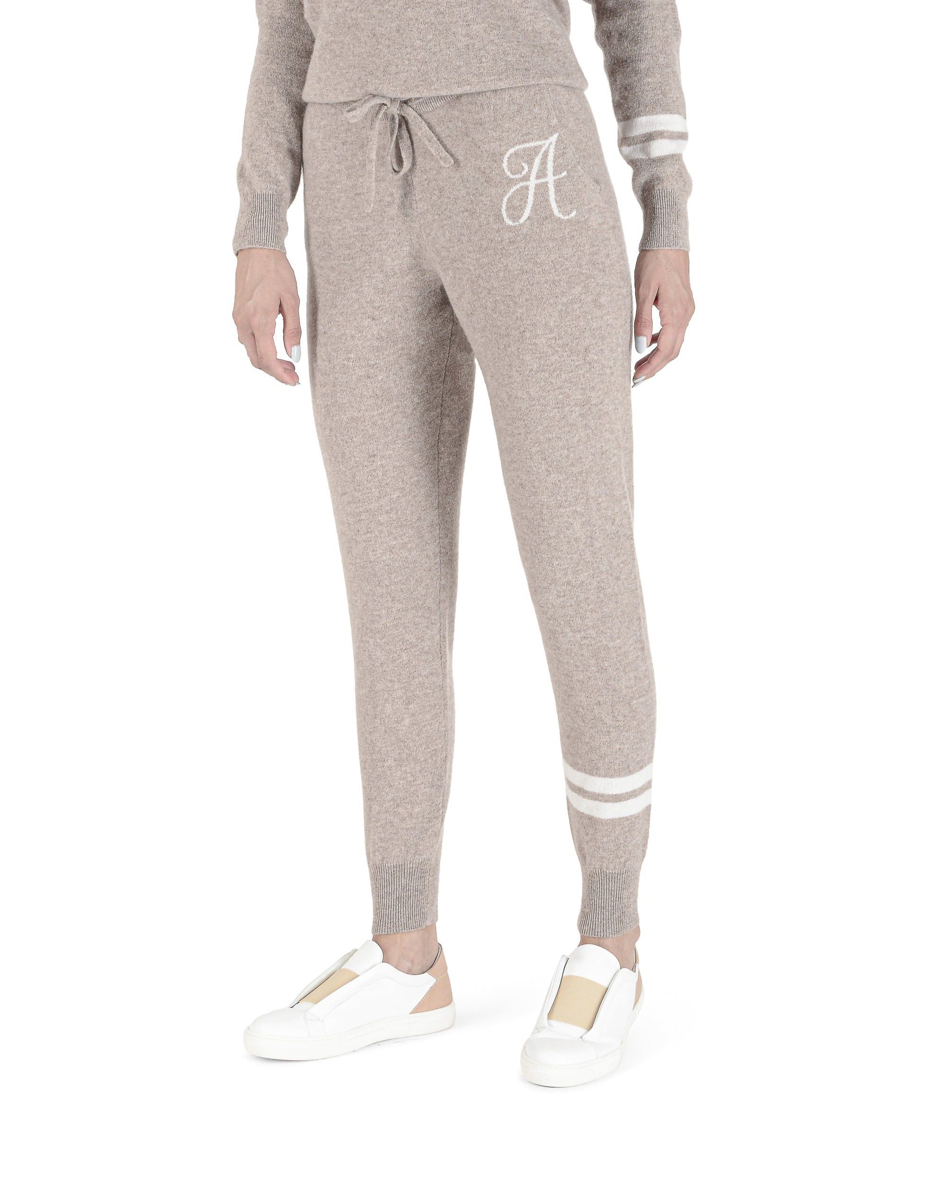 Gray jogger pants with a white monogram on a white background