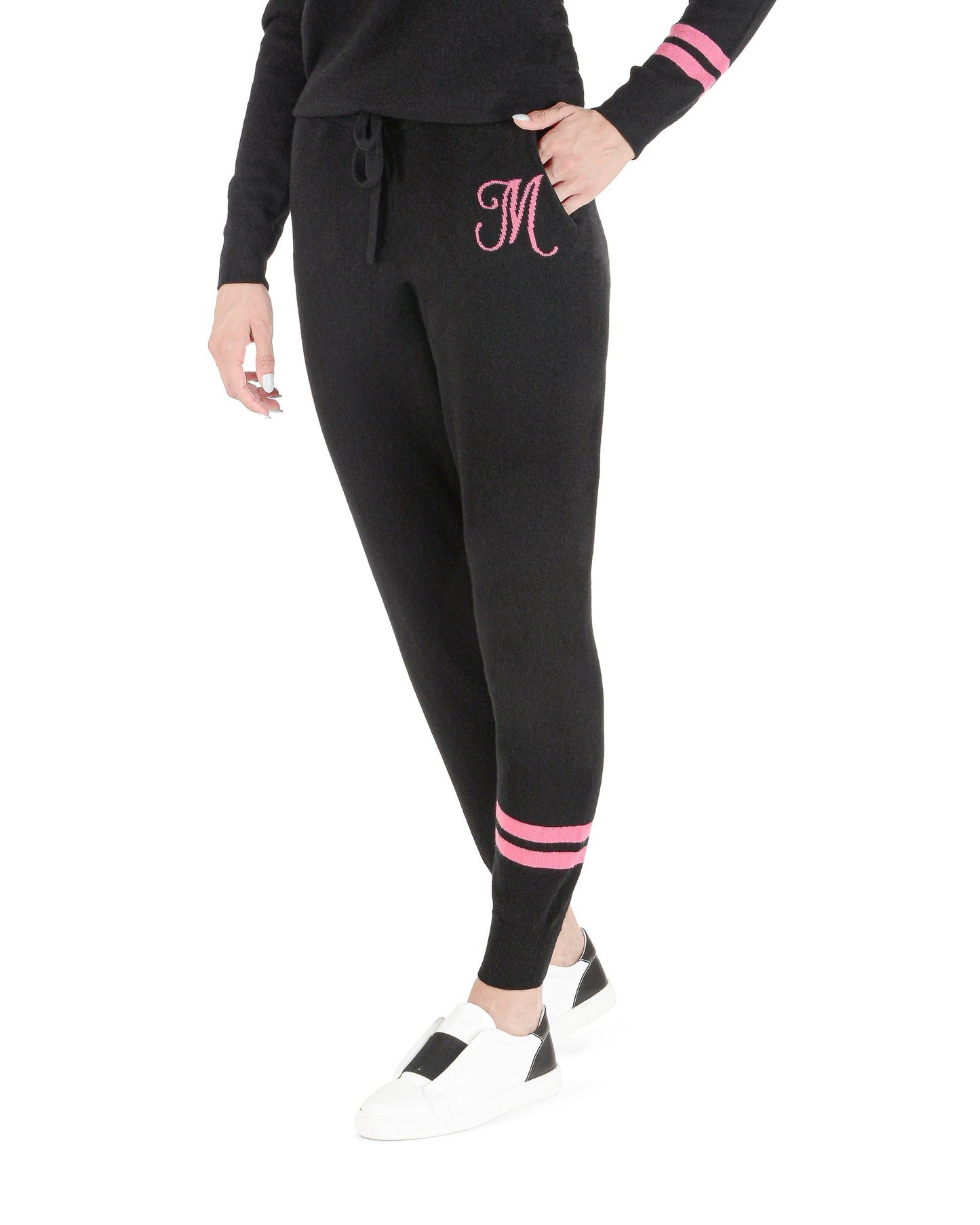 Black jogger pants with pink accents worn by a person on a white background