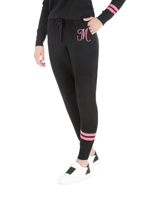 Black jogger pants with pink accents worn by a person on a white background