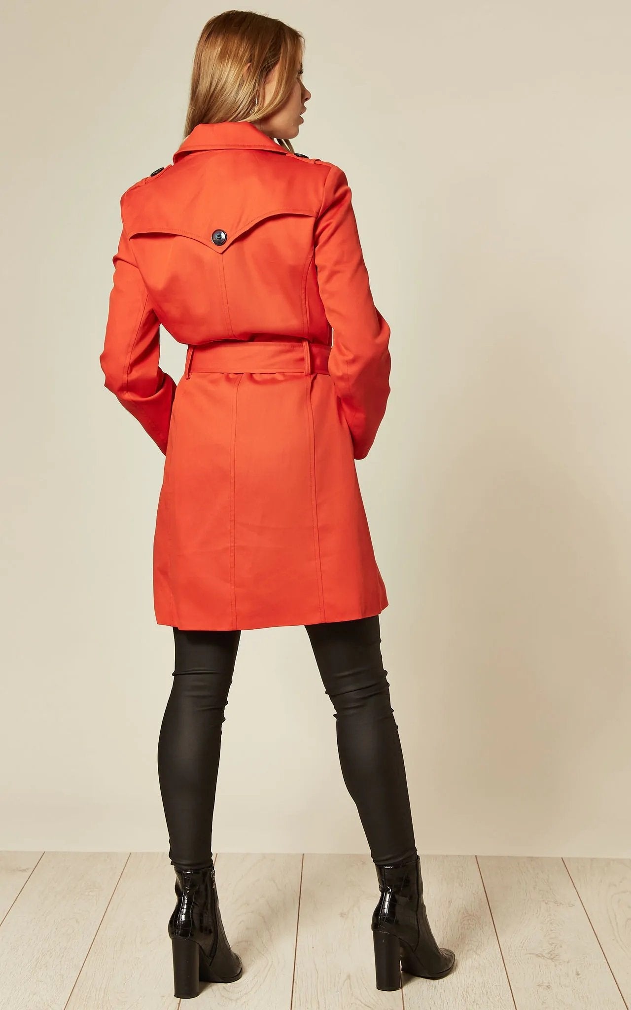 Person wearing a bright orange coat with a plain background