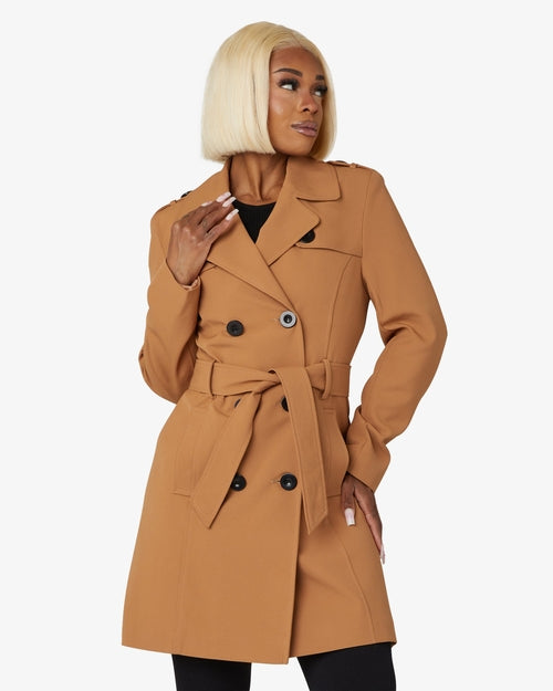Woman wearing a tan trench coat on a white background