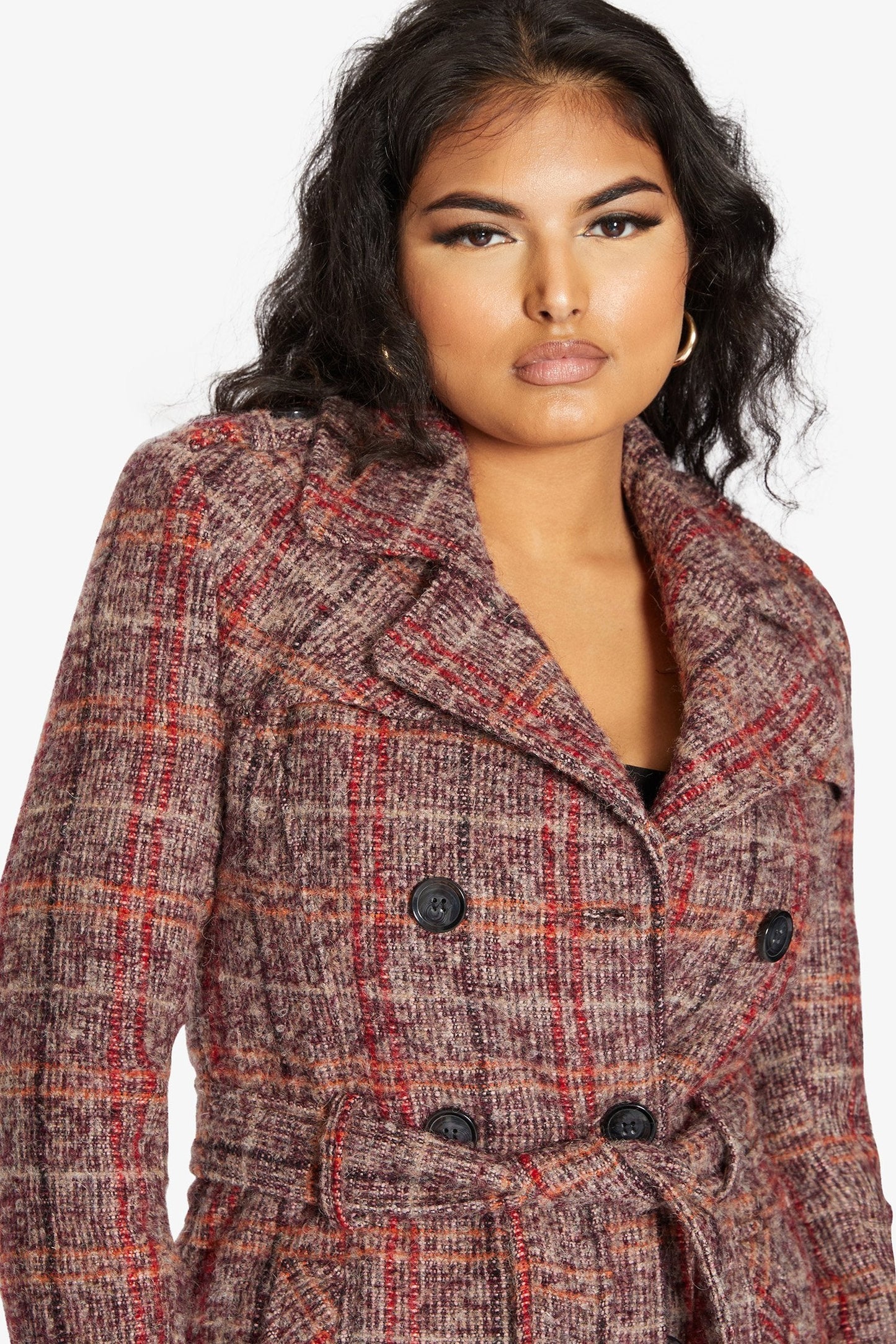 Woman wearing a plaid coat with a plain background