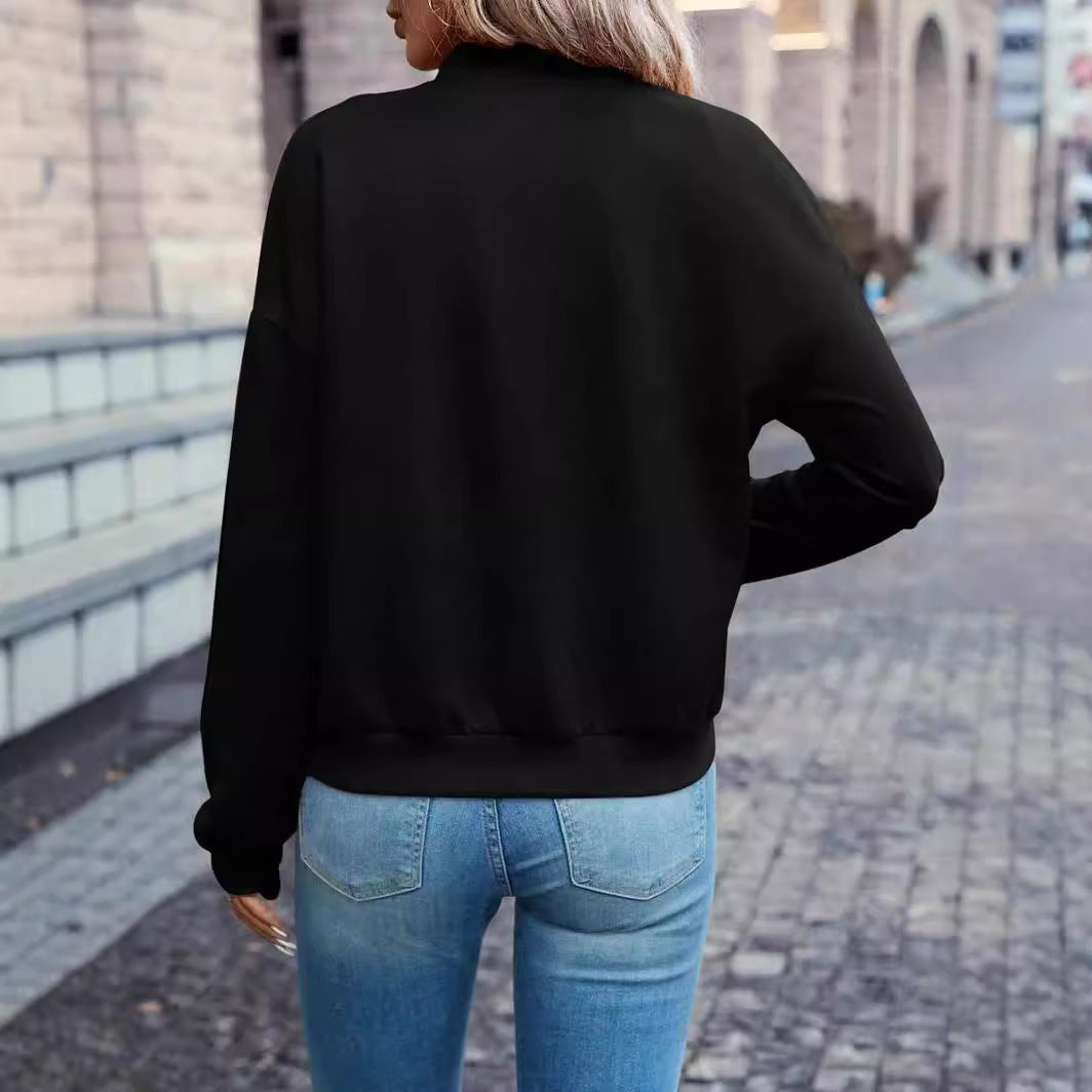 Person wearing a black jacket and blue jeans walking on a street.
