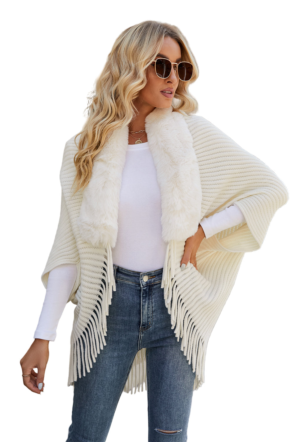 Woman wearing a cream-colored fringe cardigan over a white top and jeans on a white background