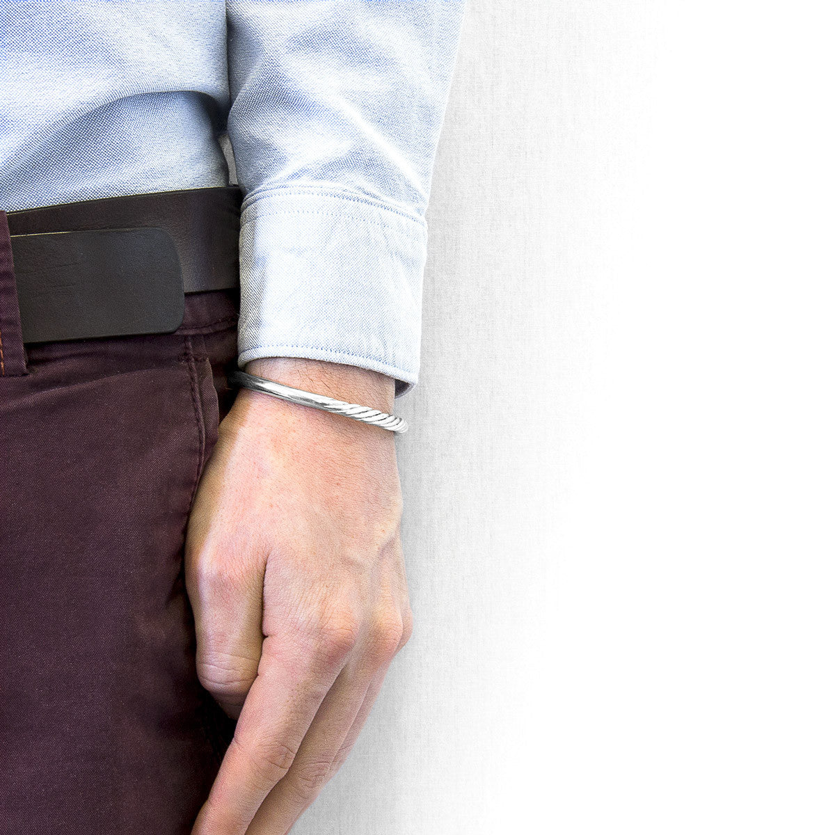 Person wearing a silver bracelet on a plain background