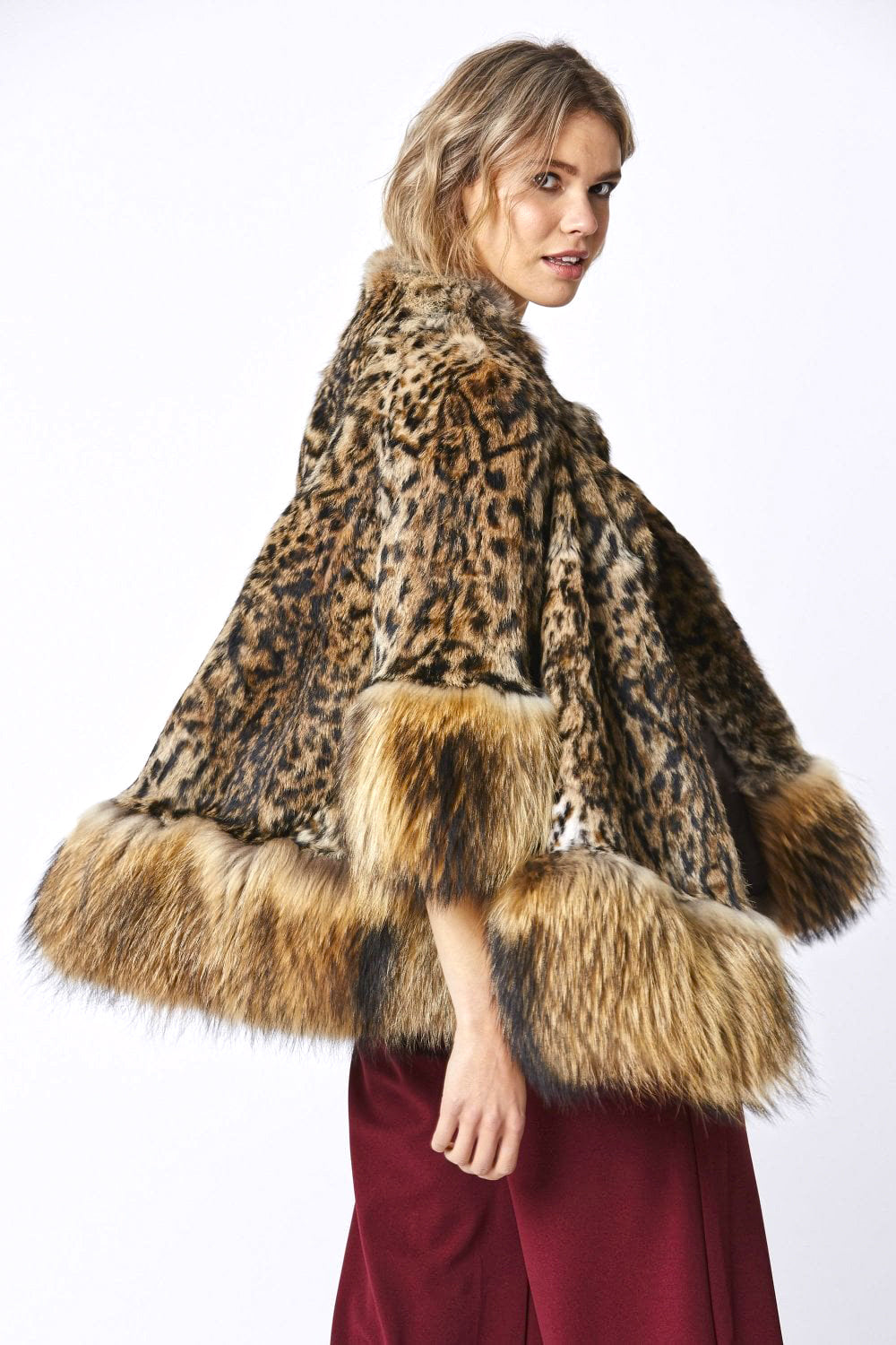 Woman wearing a leopard print fur coat with red dress underneath on a white background