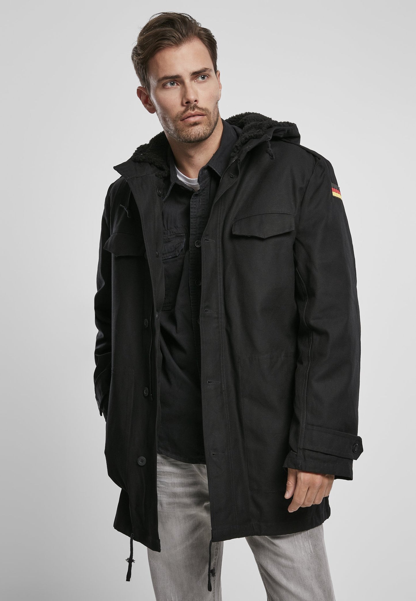 Man wearing a black parka with a hood on a light gray background