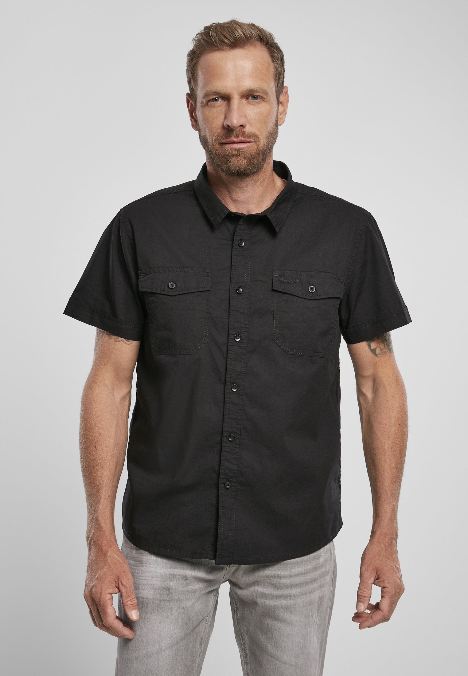 Man wearing a black short-sleeve shirt against a plain background