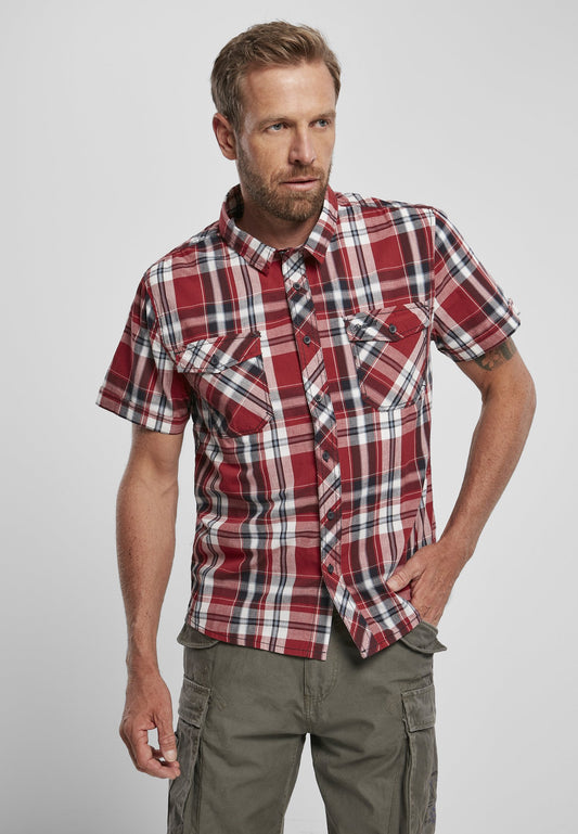 Man wearing a red plaid shirt and green pants on a gray background