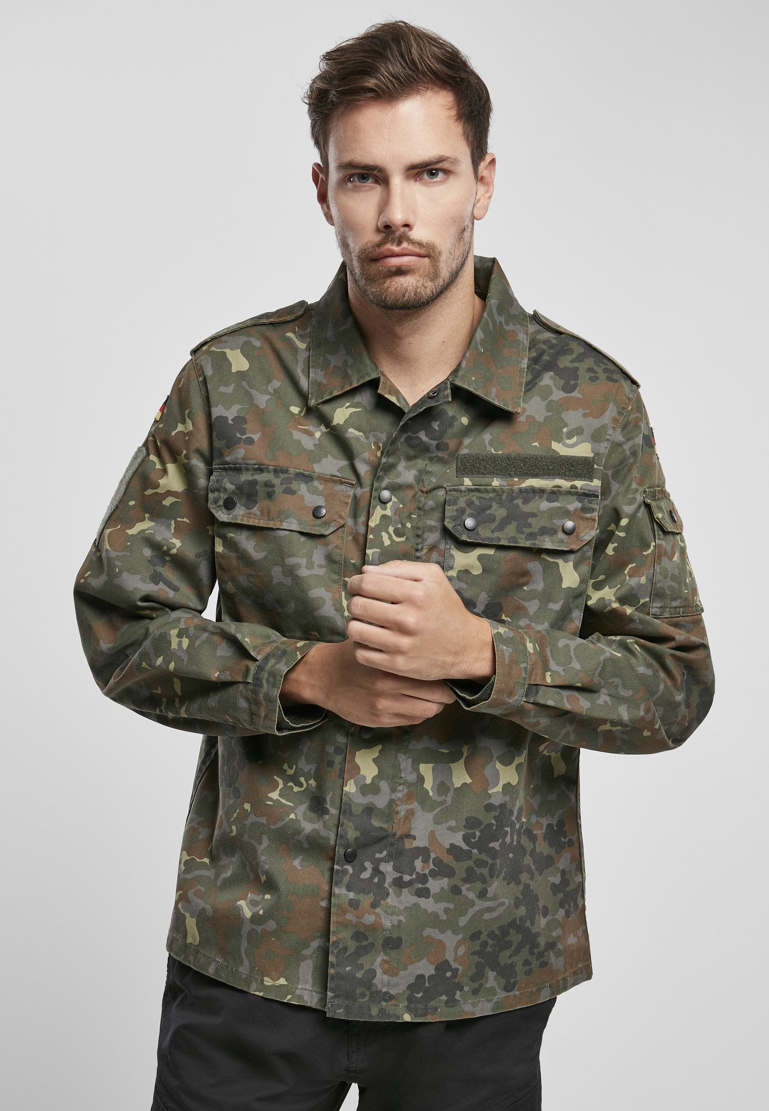 Man wearing a camouflage jacket on a light gray background