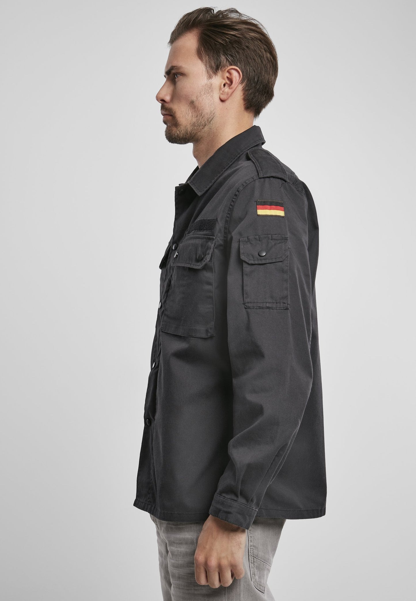 Man wearing a black jacket with a flag patch on a light gray background