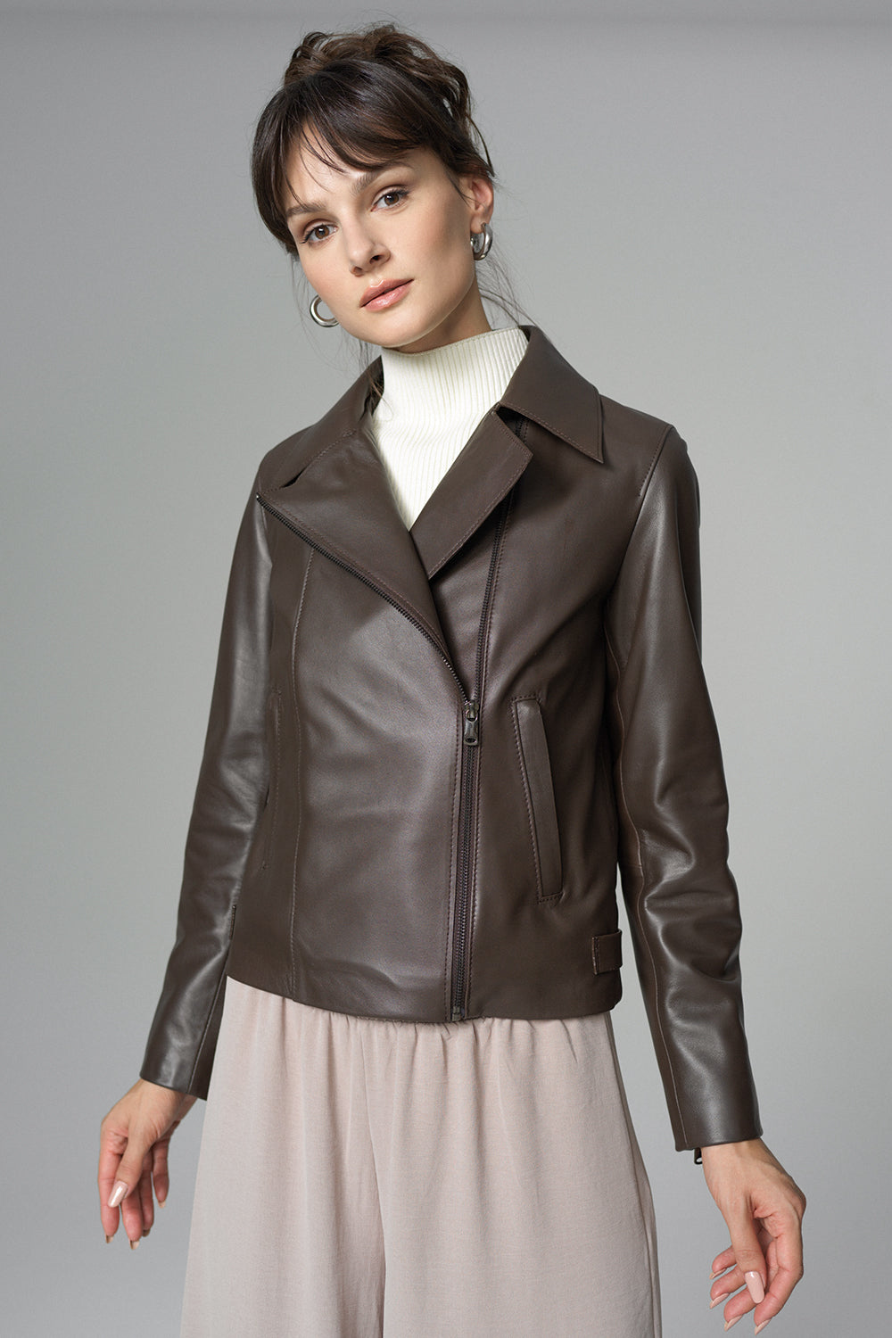 Woman wearing a brown leather jacket on a gray background