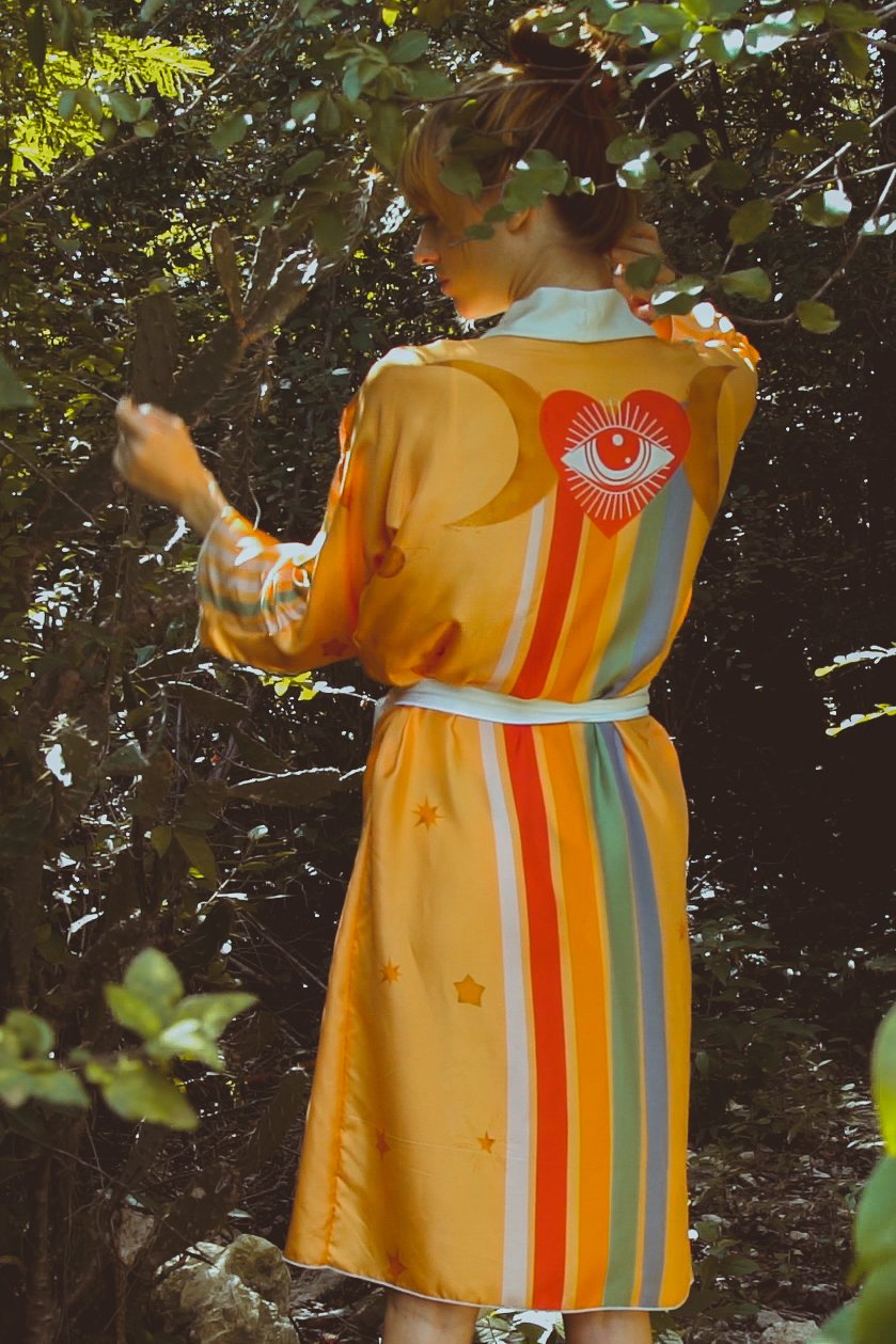 Person wearing a colorful dress with a heart design in a forest setting