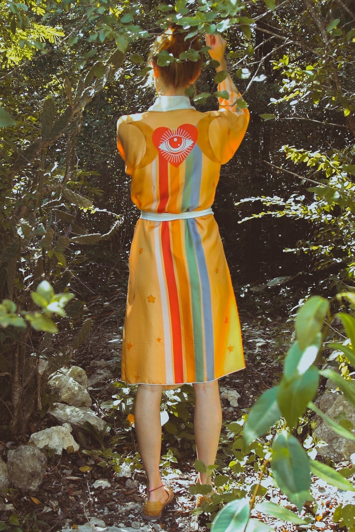Person wearing a colorful dress with a heart design in a forest setting