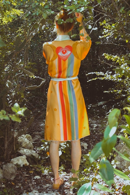 Person wearing a colorful dress with a heart design in a forest setting