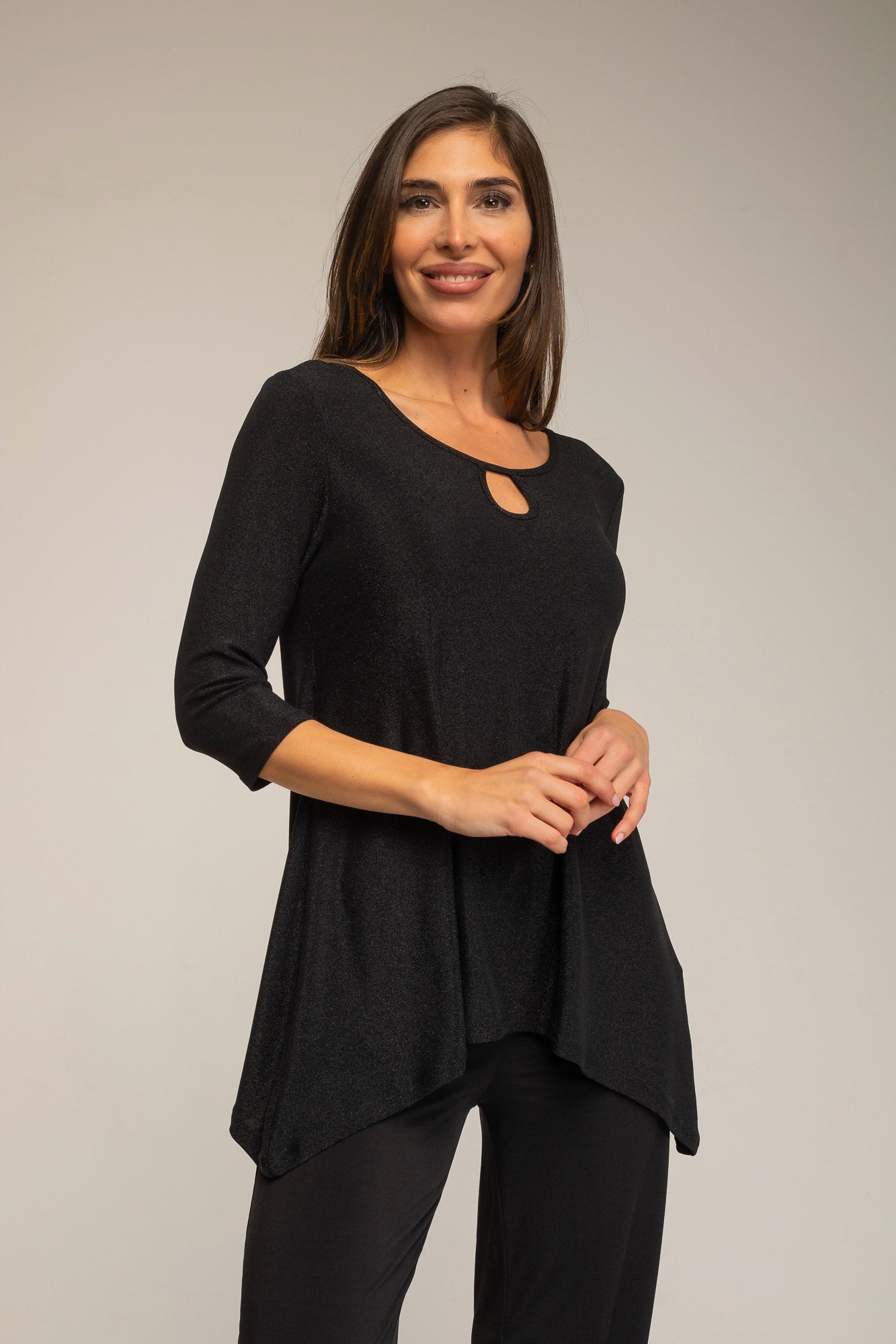 Woman wearing a black top and pants against a plain background