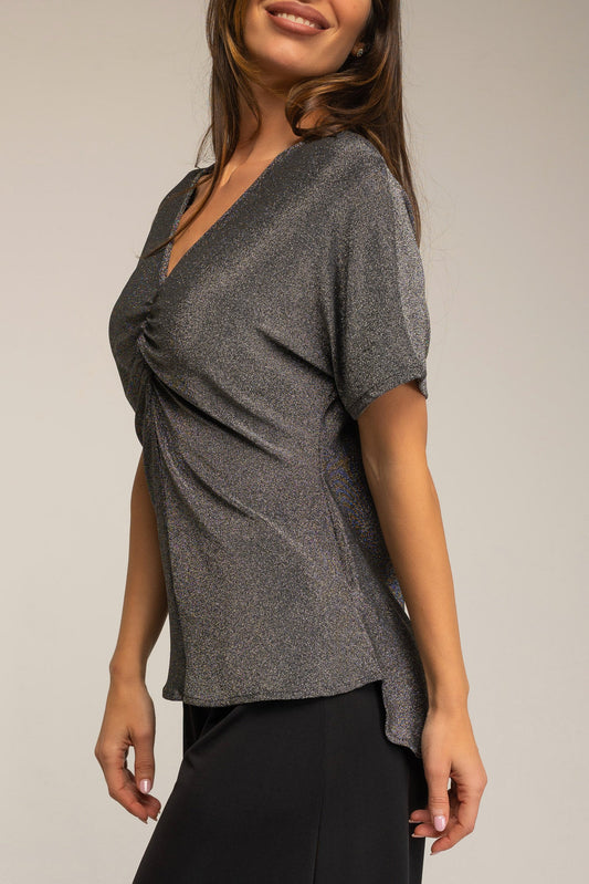 Woman wearing a gray short-sleeve top against a plain background