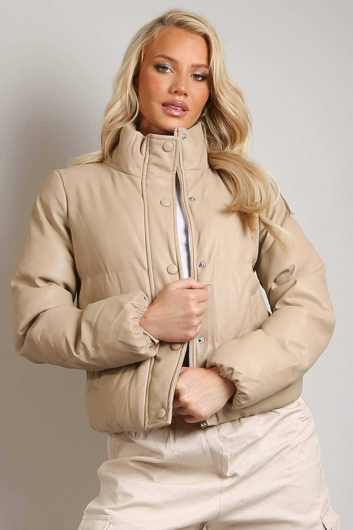 Woman wearing a beige jacket against a plain background