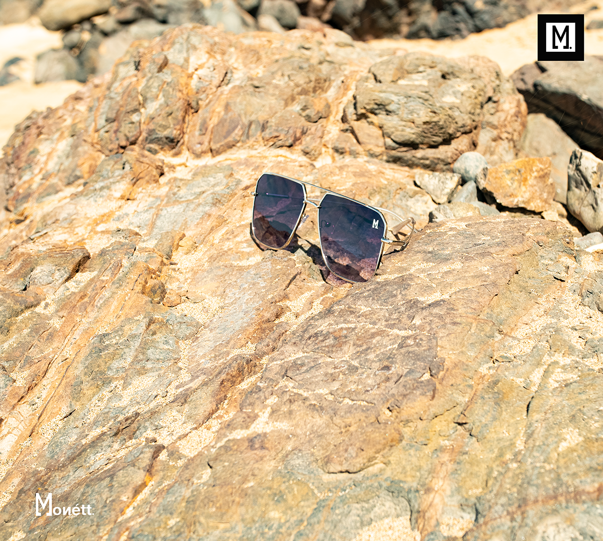 Sunglasses on a rocky surface with 'Monett' branding.