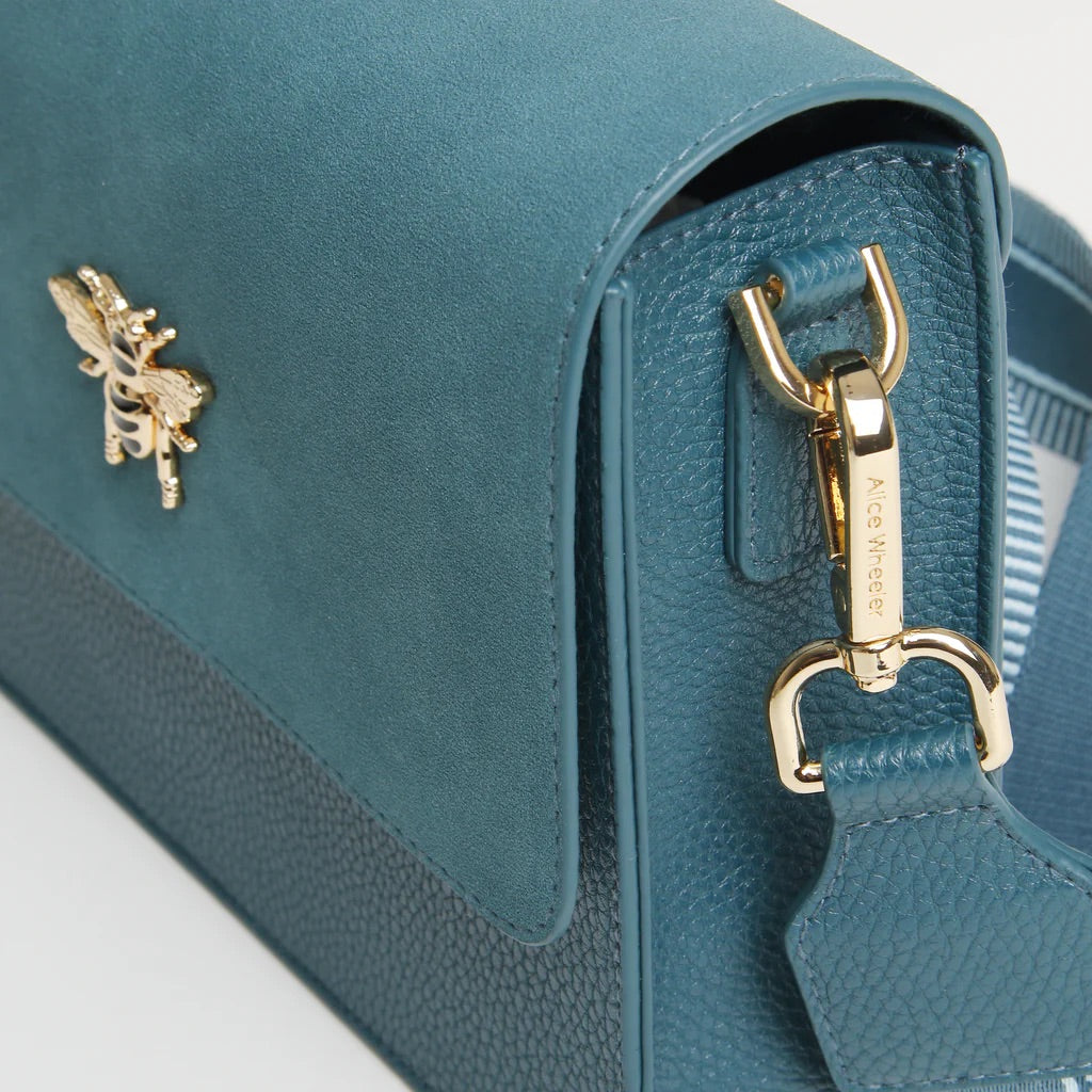 Teal handbag with gold accents on a light gray background