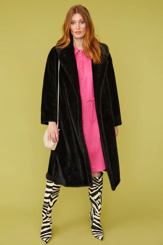 Woman wearing a black coat, pink dress, and zebra-striped boots on a green background