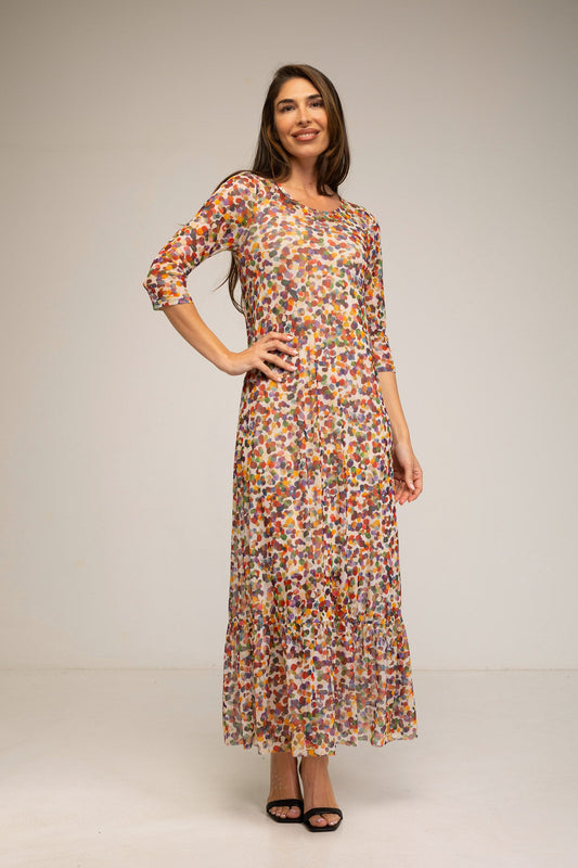 Woman wearing a colorful patterned dress on a plain background