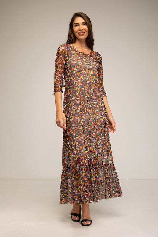 Woman wearing a long, patterned dress against a plain background