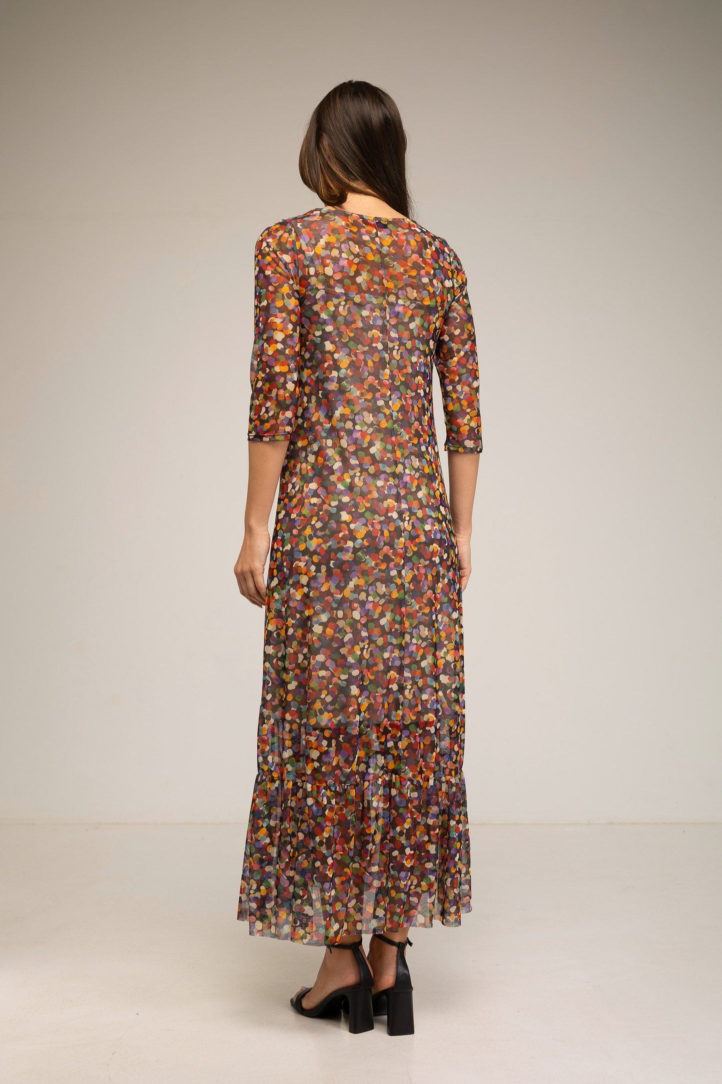 Woman wearing a long, patterned dress against a plain background