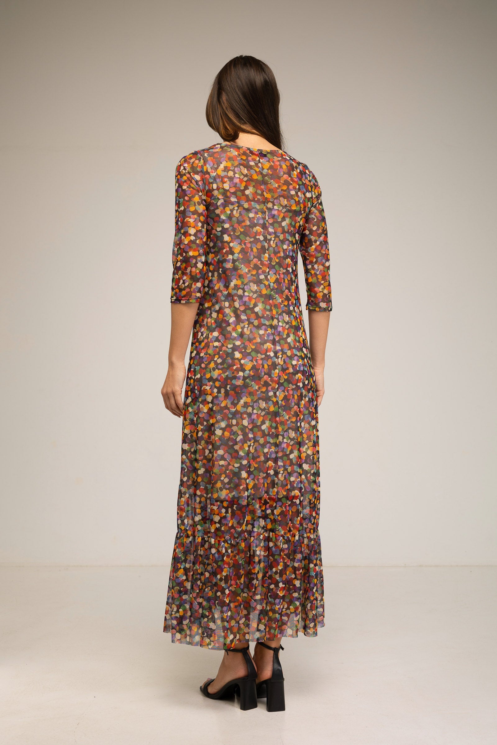 Woman wearing a long, patterned dress against a plain background