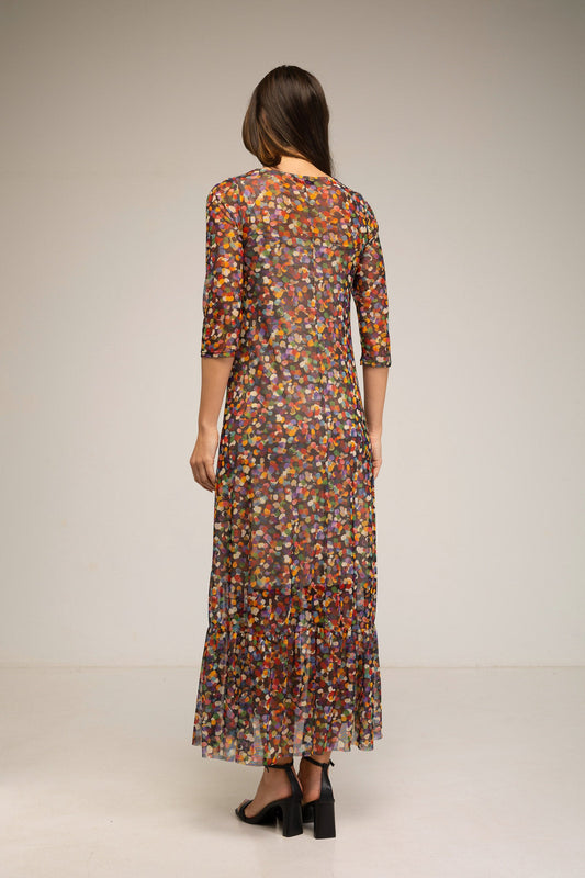 Woman wearing a long, patterned dress against a plain background