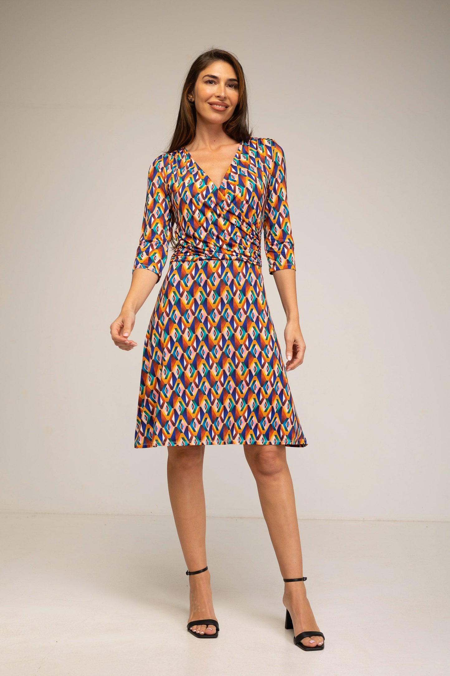 Woman wearing a colorful patterned dress on a plain background