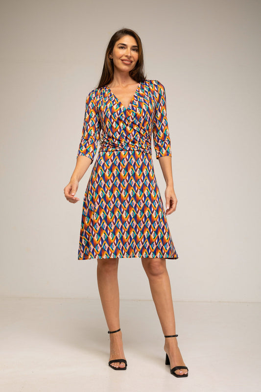 Woman wearing a colorful patterned dress on a plain background