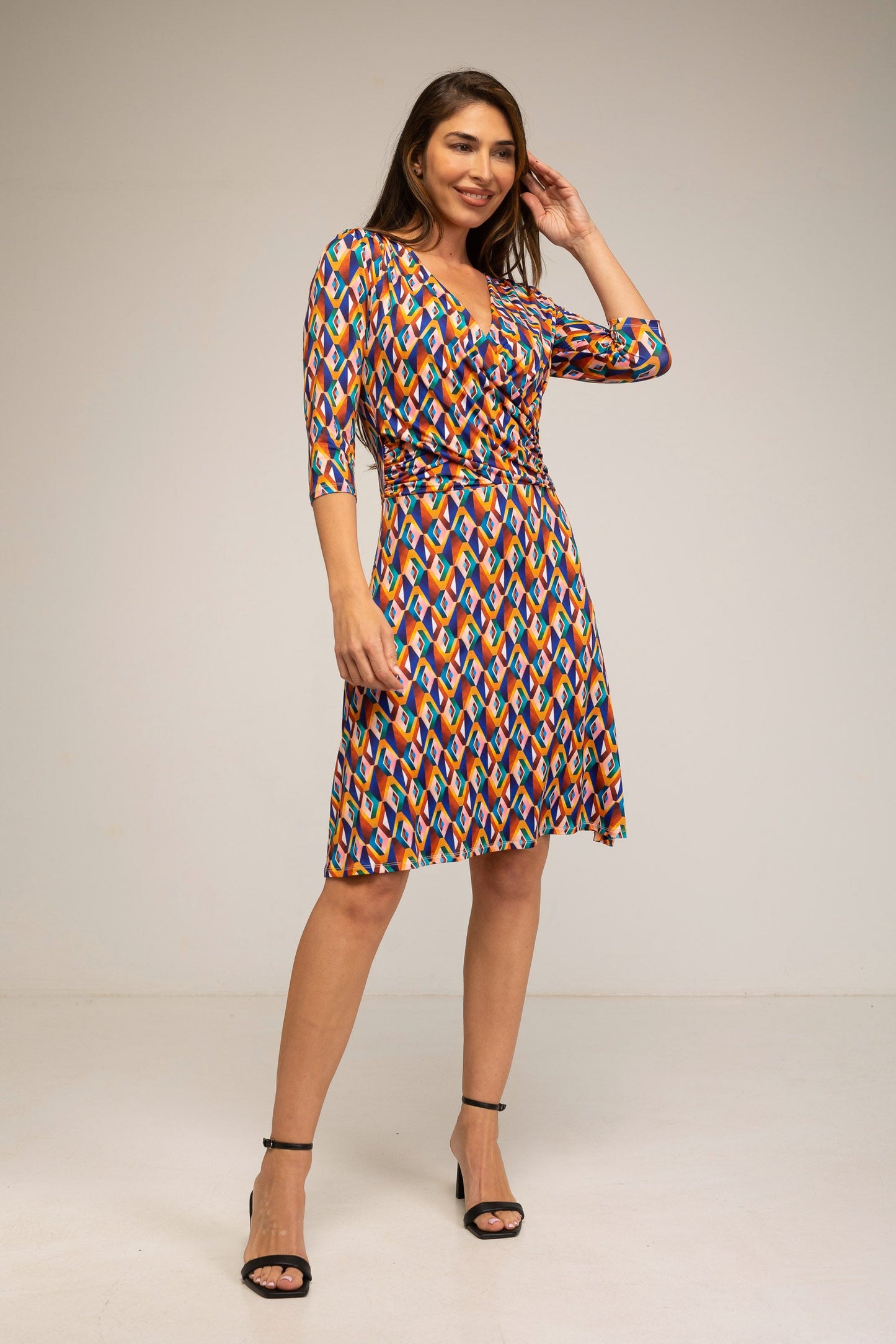 Woman wearing a colorful patterned dress on a plain background