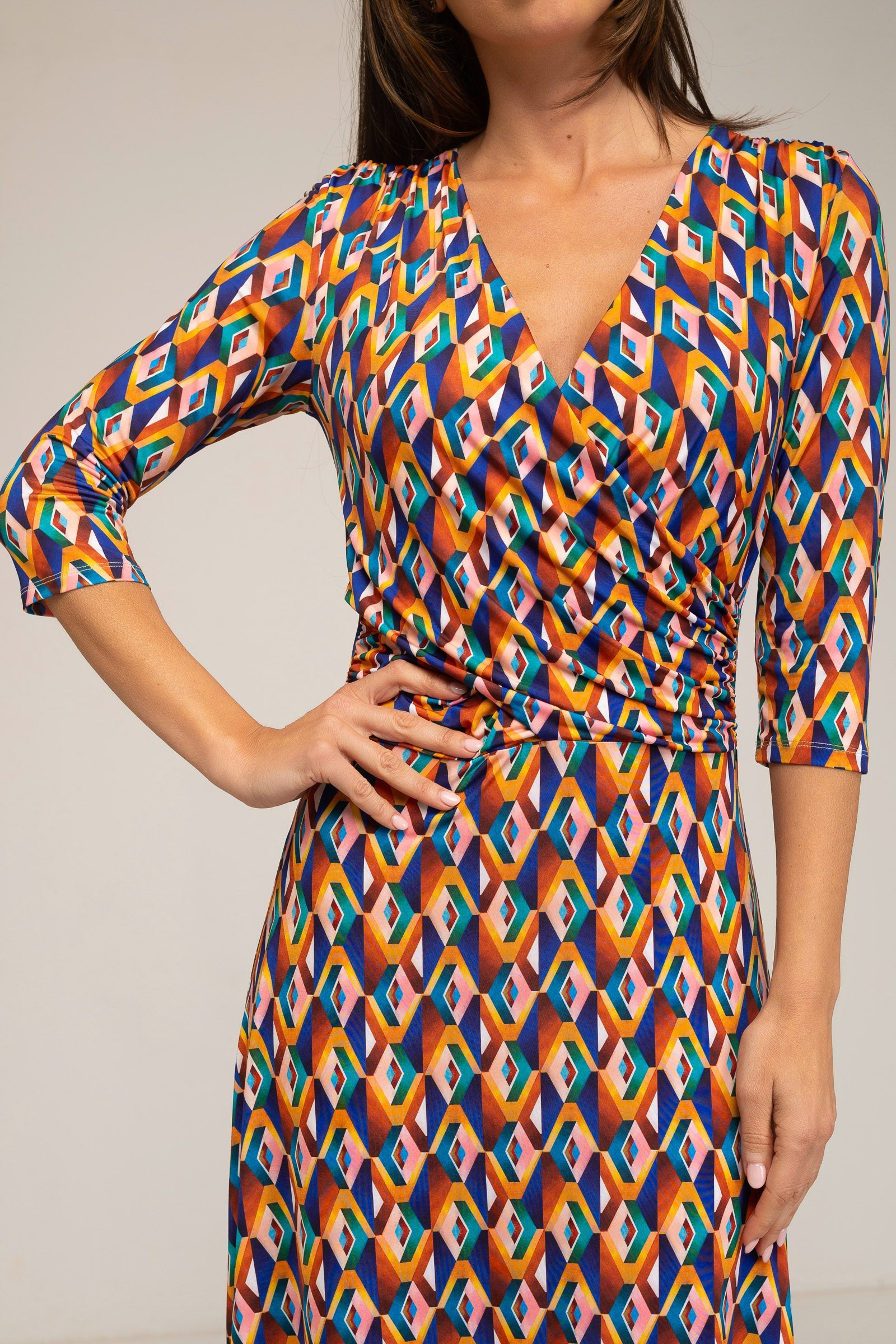 Woman wearing a colorful geometric patterned dress against a plain background