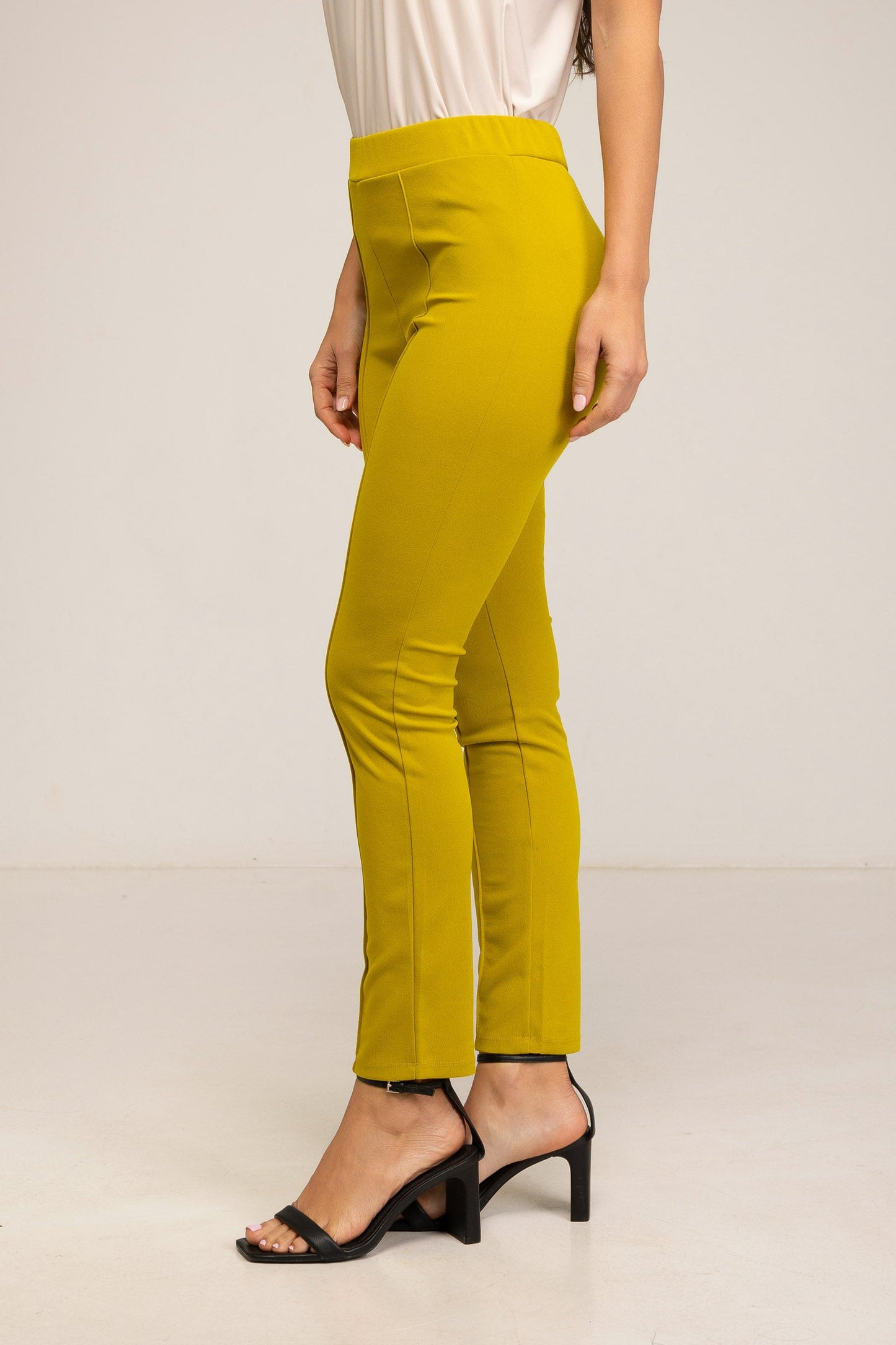 Yellow pants worn by a person on a plain background