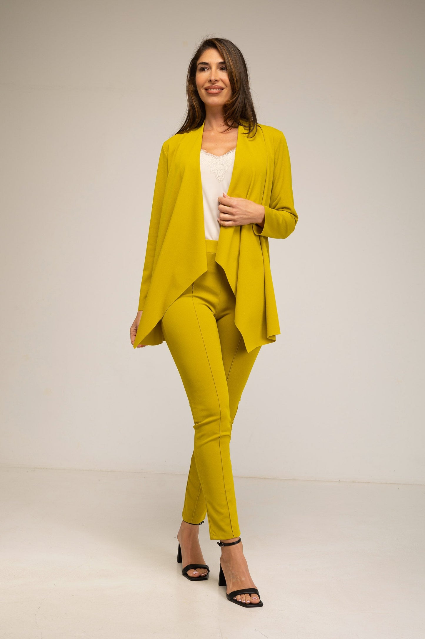Woman wearing a yellow suit standing against a plain background
