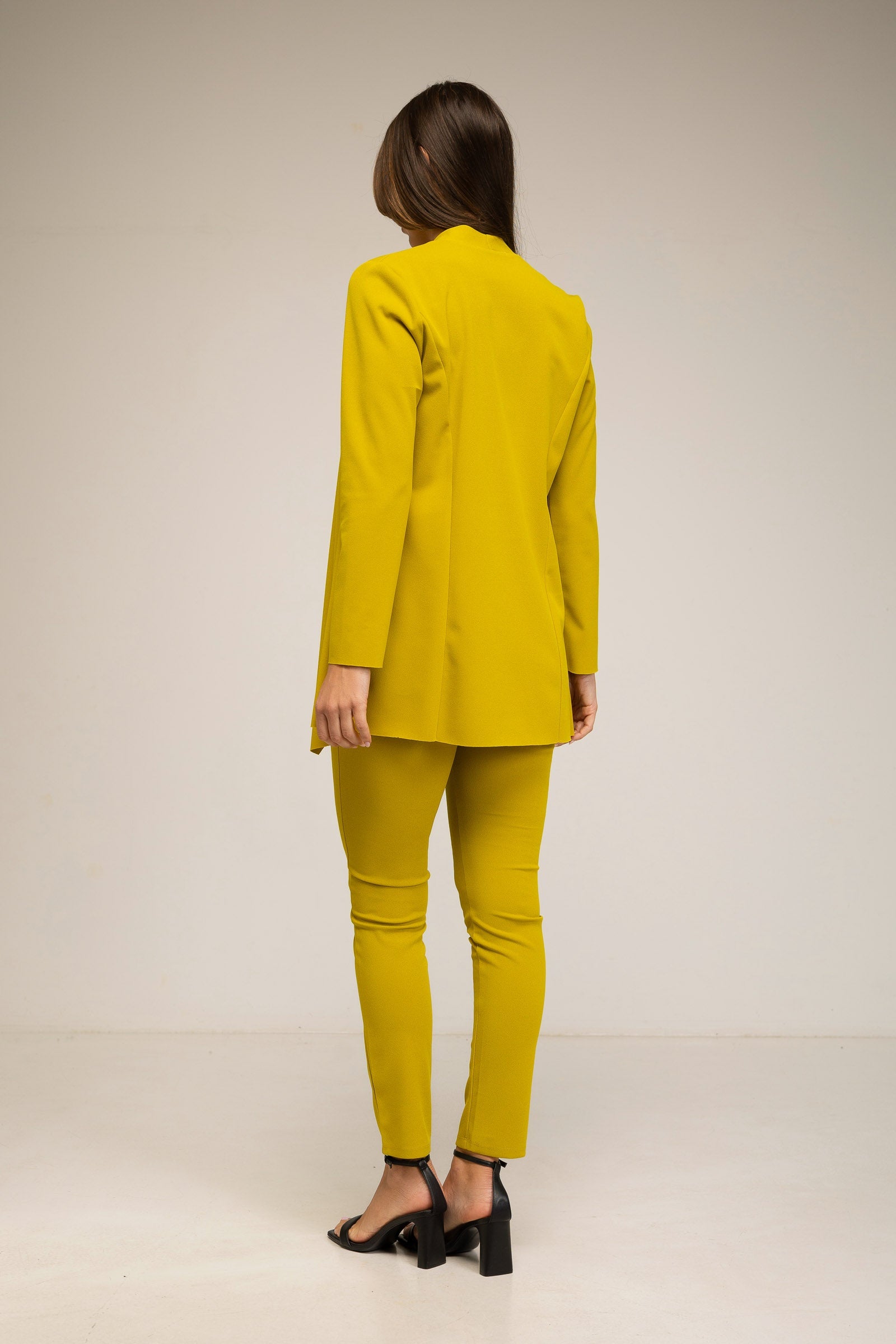 Person wearing a yellow suit standing against a plain background