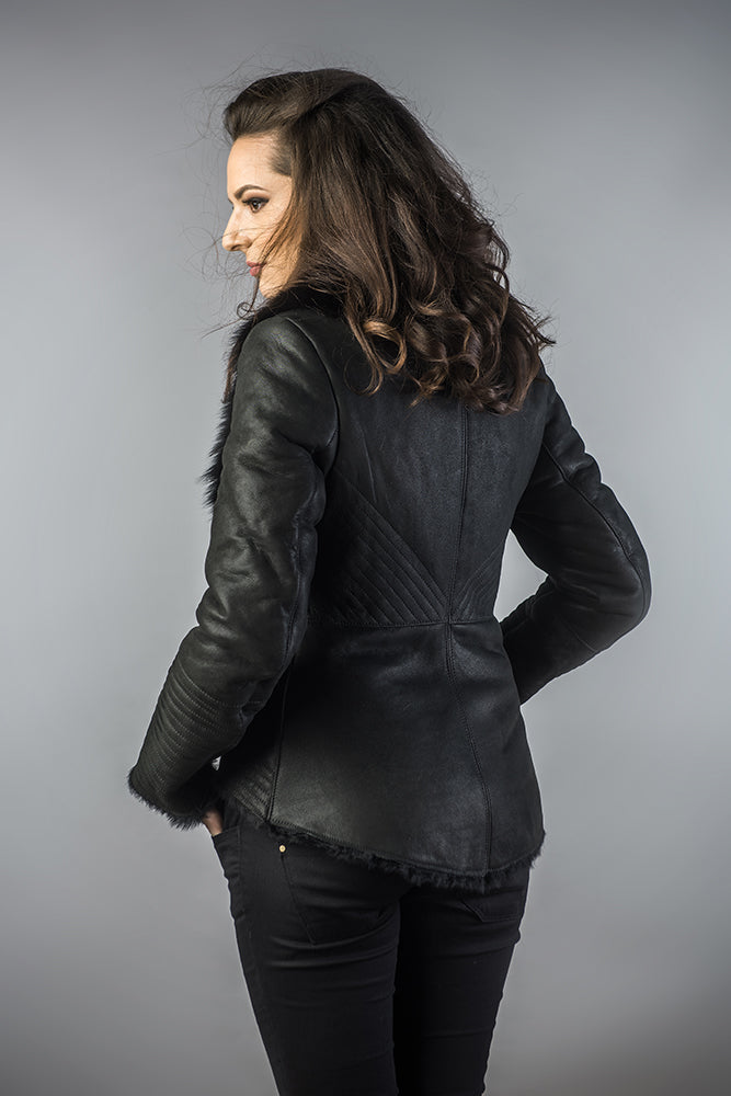 Woman wearing a black leather jacket against a gray background