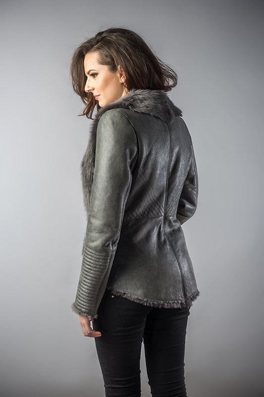 Woman wearing a gray leather jacket with fur trim on a gray background