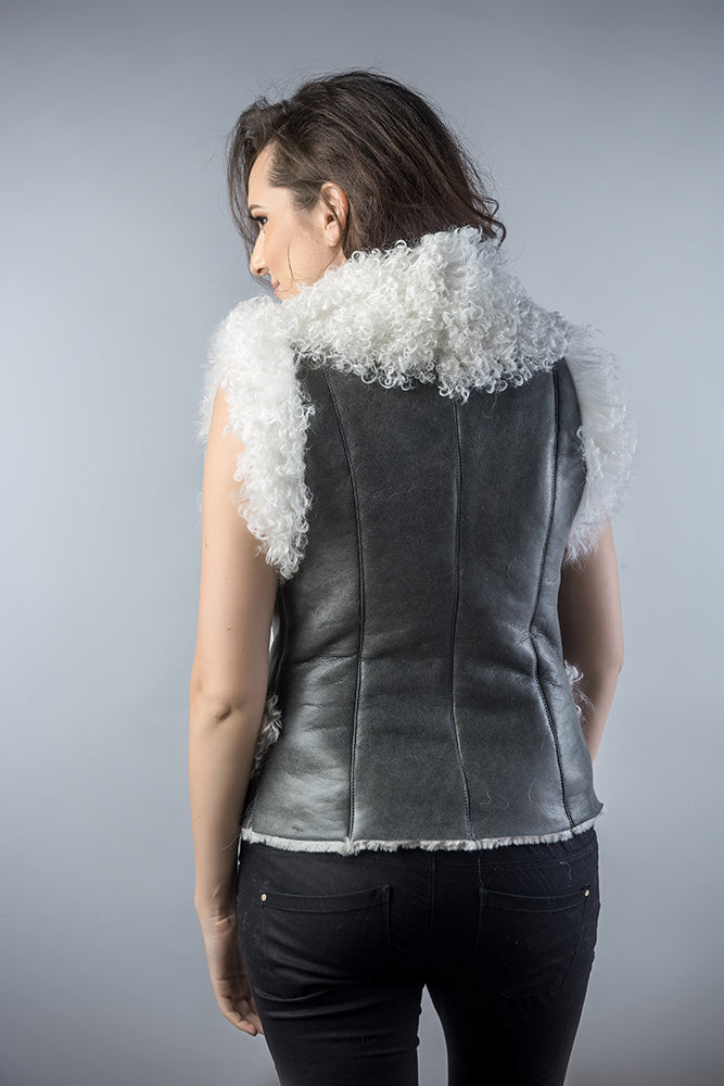 Person wearing a gray leather vest with white fur trim on a plain background