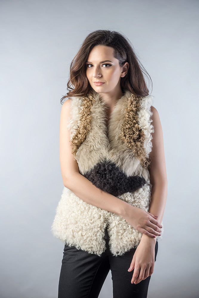 Woman wearing a white fur vest with brown accents against a gray background