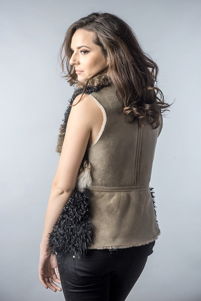 Woman wearing a brown leather vest with fur trim on a gray background