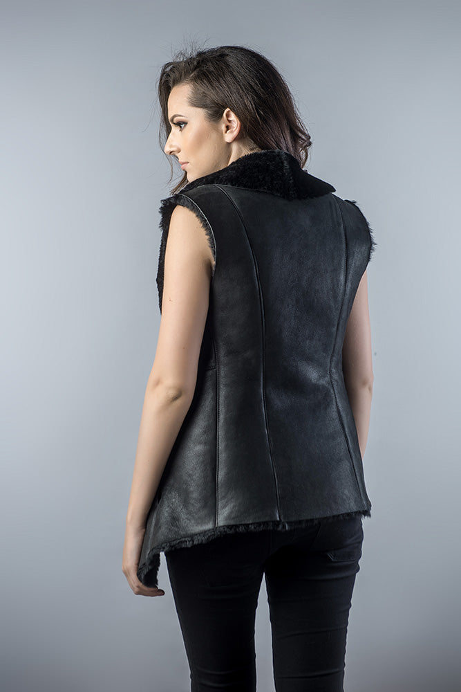Woman wearing a black leather vest against a gray background