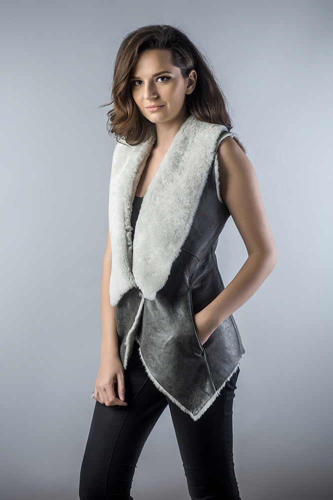 Woman wearing a gray vest with a white fur collar against a gray background