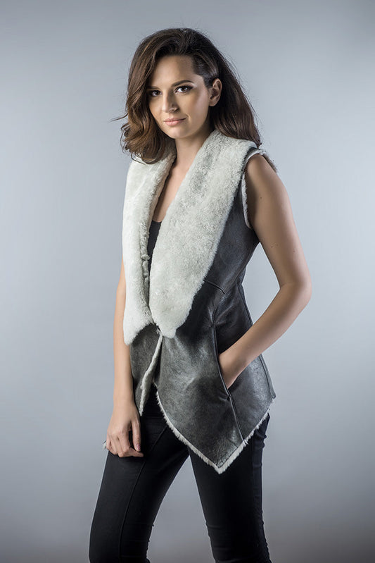 Woman wearing a gray vest with a white fur collar against a gray background