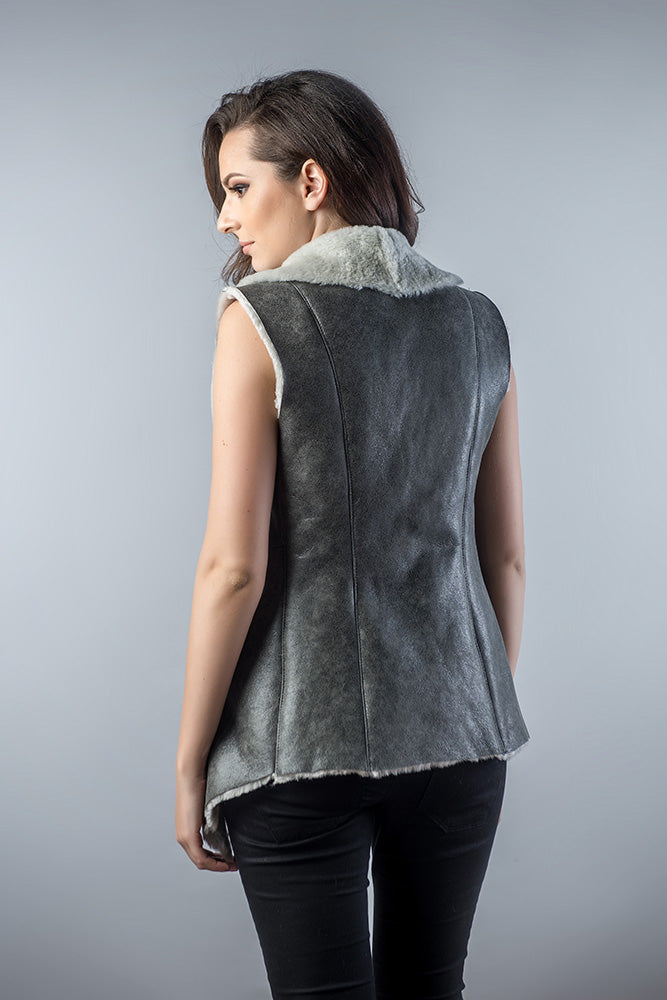 Woman wearing a gray sleeveless jacket with fur lining on a gray background
