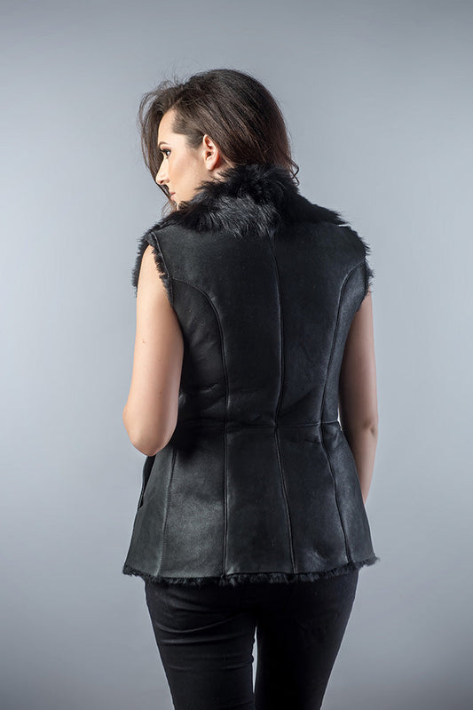 Woman wearing a black leather vest with fur trim on a gray background